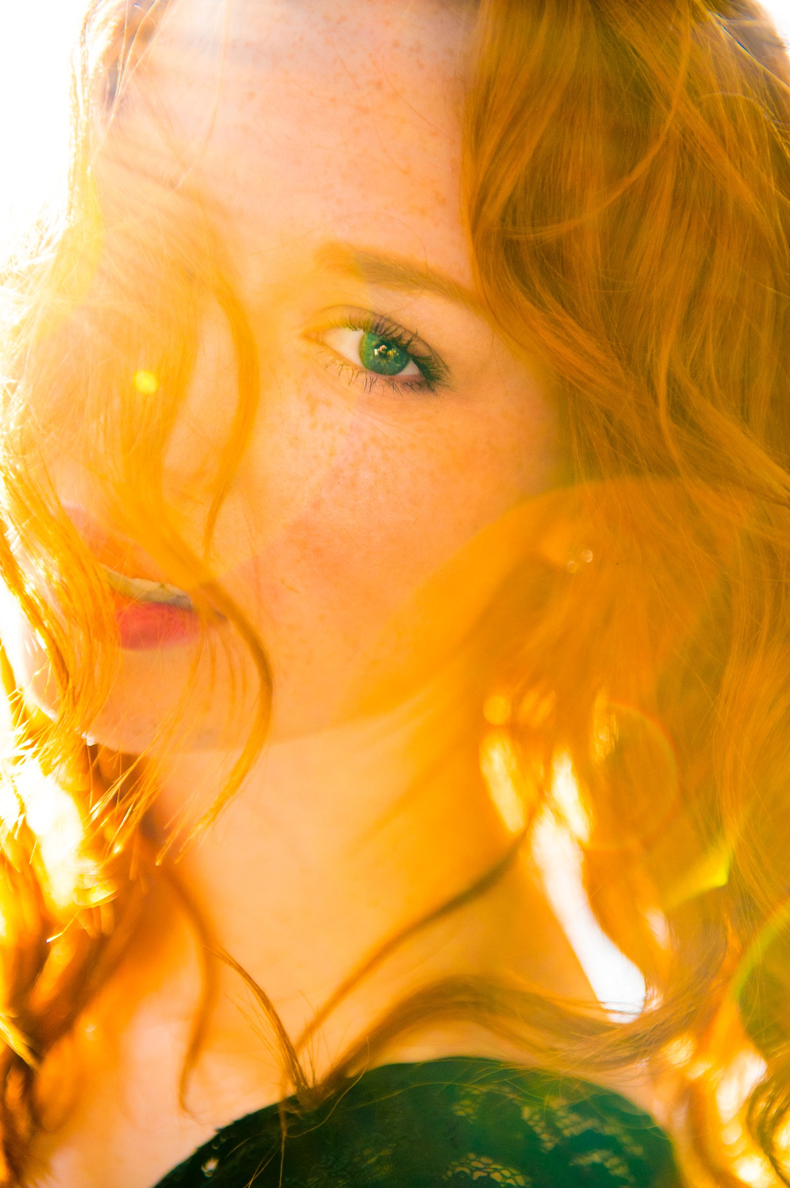 Red hair in golden backlight, one green eye through the veil — beauty study